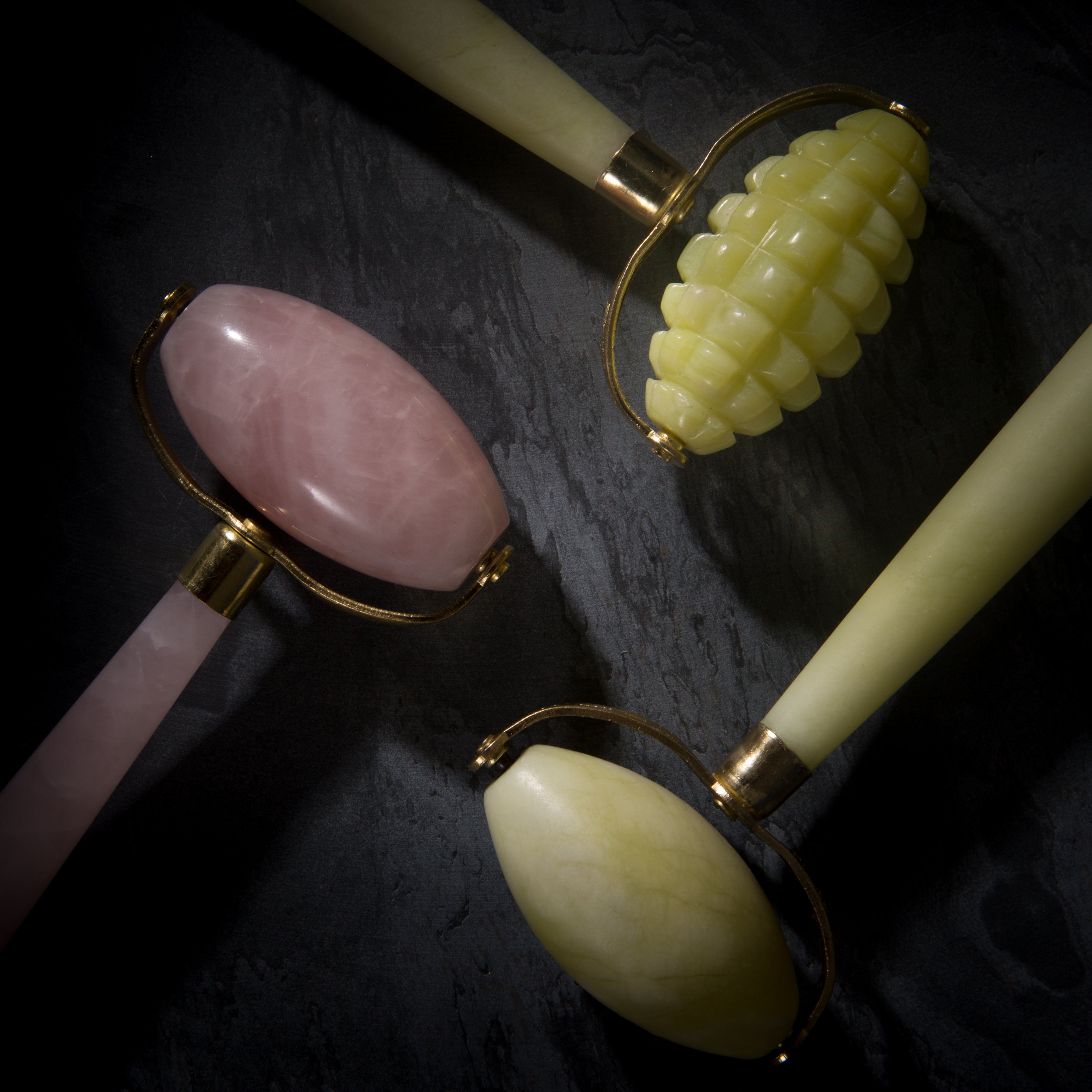 White Lotus jade and rose quartz crystal roller heads with metal safety brackets close up